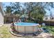 Above-ground pool nestled in a landscaped yard with tiki hut, and backyard fencing for added privacy at 275 S Highland Ave, Tarpon Springs, FL 34689