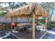 Backyard tiki hut featuring outdoor sectional seating, dining table, and access to a play area at 275 S Highland Ave, Tarpon Springs, FL 34689