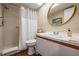 Well-lit bathroom featuring a shower stall with white tile, a toilet, and a stylish round mirror at 3076 Eastland Blvd # 305, Clearwater, FL 33761