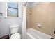 Bright bathroom features neutral tiled walls, a shower-tub combination and a toilet under the window at 3226 Cordoba Ranch Blvd, Lutz, FL 33559