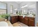 Bathroom featuring wood cabinets, granite countertops, dual sinks, large mirrors, and a soaking tub beneath a bright window at 3226 Cordoba Ranch Blvd, Lutz, FL 33559