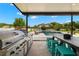 The patio is equipped with an outdoor kitchen, a table with seating, and a swimming pool at 3226 Cordoba Ranch Blvd, Lutz, FL 33559