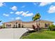 Charming tan home with a terracotta-tiled roof, beautiful landscaping, and a lengthy driveway approach at 3487 Recurve Cir, Sarasota, FL 34240