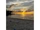 Golden sunset casting a warm glow over the beach and water, silhouetting trees and a distant sailboat at 3735 42Nd S Way # J, St Petersburg, FL 33711