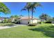 View of the home's side featuring mature palm trees, well-kept lawn, and an attached two-car garage at 4904 Breyer Wood Ct, Valrico, FL 33596
