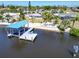 Aerial view showcases a private dock with boatlift, lounge chairs, and lush landscaping by calm waters at 810 Blue Heron Blvd, Ruskin, FL 33570