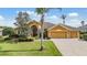 Inviting front exterior of home with well-manicured lawn and a three-car garage at 13514 Thoroughbred Dr, Dade City, FL 33525