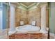 Luxurious bathroom with a stone-accented, triangular soaking tub and decorative columns at 1408 Alhambra Dr, Apollo Beach, FL 33572