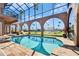 Beautiful in-ground swimming pool with screened enclosure, archways, and sun lounge area at 1408 Alhambra Dr, Apollo Beach, FL 33572