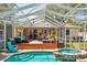 Outdoor entertaining space features a pool, spa, screened enclosure, and a wood deck with comfortable furniture at 1808 Gray S St, Gulfport, FL 33707