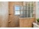 Tiled walk-in shower featuring decorative glass block detail, tiled walls, a window and corner shelving at 1808 Gray S St, Gulfport, FL 33707