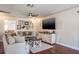 Bright living room features a ceiling fan, dark wood floors, a neutral colored couch, and a large tv at 1828 Stancel Dr, Clearwater, FL 33764