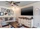 A cozy living room features a ceiling fan, dark wood floors, a neutral couch and mounted television at 1828 Stancel Dr, Clearwater, FL 33764