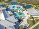 Aerial view of a resort-style pool with palm trees, cabanas, and a nearby lake at 19212 Iron Topsail Isle, Land O Lakes, FL 34638