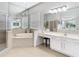 Bright bathroom featuring a large tub, walk-in shower, white vanity, and ample mirror space at 2327 Shirecrest Cove Way, Lutz, FL 33558