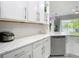 Well-lit kitchen with white cabinets, modern stainless steel dishwasher, and quartz countertops at 2327 Shirecrest Cove Way, Lutz, FL 33558