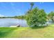 Scenic lake view showcasing a grassy shoreline with trees, clear blue skies, and a dock for recreational activities at 2327 Shirecrest Cove Way, Lutz, FL 33558