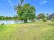 Backyard with lush green grass leading to a serene lake with a dock, creating an ideal outdoor oasis at 2327 Shirecrest Cove Way, Lutz, FL 33558