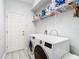 Modern laundry room featuring a front-loading washer and dryer, with convenient overhead shelving for supplies at 2327 Shirecrest Cove Way, Lutz, FL 33558