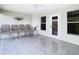 Open-air patio with tile flooring, ceiling fan, four chairs, and a view of the outdoors through windows and a door at 2327 Shirecrest Cove Way, Lutz, FL 33558
