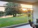 Screened patio view overlooking peaceful pond and lush green lawn at sunset from tiled balcony and chair at 2327 Shirecrest Cove Way, Lutz, FL 33558