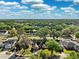 Expansive aerial view of a residential neighborhood, showcasing lush green trees and charming homes under a bright sky at 2329 Towering Oaks Cir, Seffner, FL 33584