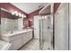 Bathroom featuring a glass shower, dual sinks, and a large mirror, with tile flooring and a maroon accent wall at 2329 Towering Oaks Cir, Seffner, FL 33584