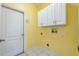 Laundry room with white cabinets, tile floors, and yellow painted walls at 2329 Towering Oaks Cir, Seffner, FL 33584