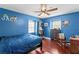 Bright bedroom with vibrant blue walls, ceiling fan, and hardwood floors offers cozy living space at 4506 W Beachway Dr, Tampa, FL 33609