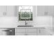 Bright kitchen with white custom cabinets, modern hardware, stainless sink and unique glass detail window at 4506 W Beachway Dr, Tampa, FL 33609