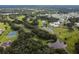 An aerial view features a golf course, a pond, tennis courts and nearby houses surrounded by mature trees at 5546 Benton St, Zephyrhills, FL 33542