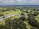 An aerial view showcases a golf course, tennis courts, and a residential neighborhood surrounded by trees at 5546 Benton St, Zephyrhills, FL 33542