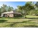 Lush backyard showcasing a well-maintained lawn, mature trees and a view of the back of the house at 7182 Griffin Rd, Brooksville, FL 34601