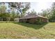 Spacious backyard with green lawn, mature trees, and back view of the house at 7182 Griffin Rd, Brooksville, FL 34601