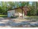 Exterior of a detached outbuilding with a covered porch, garage door, and surrounding greenery at 7182 Griffin Rd, Brooksville, FL 34601