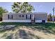 Well-maintained home with gray siding, complemented by black shutters and a manicured lawn, and mature trees at 9420 Kiowa Dr, New Port Richey, FL 34654