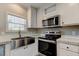 Stainless steel microwave and oven paired with a farmhouse sink and bright, white cabinets at 9420 Kiowa Dr, New Port Richey, FL 34654