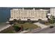 Aerial view shows the seven-story condo building with a waterfront lawn and parking spaces at 100 Bluff View Dr # 502C, Belleair Bluffs, FL 33770