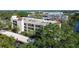 Aerial view of condo building surrounded by lush trees and water feature at 11485 Oakhurst Rd # A202, Largo, FL 33774