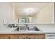 The stainless steel kitchen sink has a view of the chandelier lit living area at 11485 Oakhurst Rd # A202, Largo, FL 33774