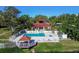 Aerial view of the community pool, gazebo, spa, community center, patio furniture, and surrounding trees at 11485 Oakhurst Rd # A202, Largo, FL 33774