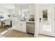 Bright kitchen featuring white cabinets, stainless steel appliances, and a view of the adjacent dining area at 1908 Sutherland W Dr, Palm Harbor, FL 34683