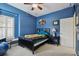 Comfortable bedroom with blue walls, ceiling fan, window shutters and sports memorabilia decor at 2676 Tanglewood Trl, Palm Harbor, FL 34685