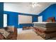 A bedroom with vibrant blue walls, a ceiling fan, and a blank projector screen create a unique space at 2676 Tanglewood Trl, Palm Harbor, FL 34685