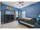 Stylish bedroom featuring blue walls, a ceiling fan, large mirror, and well-lit with window shutters at 2676 Tanglewood Trl, Palm Harbor, FL 34685