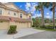Charming townhome featuring a red tile roof, two-car garage, and mature palm trees adding a tropical touch at 2676 Tanglewood Trl, Palm Harbor, FL 34685