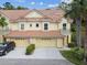 Charming two-story townhome featuring a tile roof, one-car garage, well-maintained landscaping, and covered front entrance at 2676 Tanglewood Trl, Palm Harbor, FL 34685