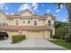 Charming townhome featuring a red tile roof, two-car garage, and beautifully landscaped front yard with an American flag at 2676 Tanglewood Trl, Palm Harbor, FL 34685