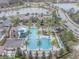 Aerial view of community pool, clubhouse, palm trees, recreation area, and surrounding lakes and landscape at 28923 Lucero Ln, Wesley Chapel, FL 33543