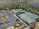 Overhead view of community tennis courts, parking lot, landscaping and mature trees on a sunny day at 28923 Lucero Ln, Wesley Chapel, FL 33543